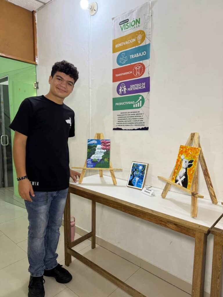 Estudiante posa junto a tres pinturas exhibidas durante la celebraci&oacute;n del aniversario