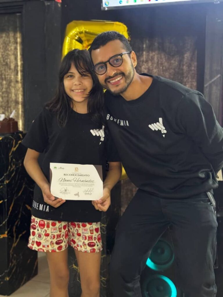 Noem&iacute; Hern&aacute;ndez posa junto a un instructor mientras sostiene un reconocimiento