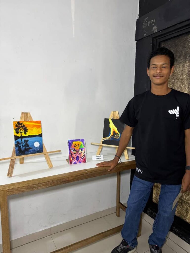 &Aacute;ngel Torres posa junto a tres trabajos art&iacute;sticos presentados durante la exhibici&oacute;n