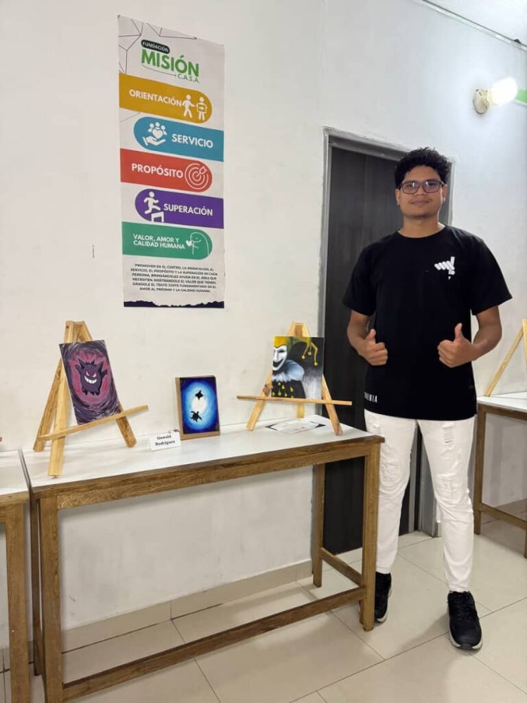 Oswald Rodr&iacute;guez posa junto a tres obras de arte exhibidas durante el aniversario del Centro Art&iacute;stico Bohemia
