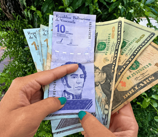 Billetes venezolanos y dólares estadounidenses sostenidos por una persona