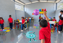 Niños de preescolar participan en actividades dentro de un aula escolar junto a una docente.