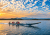 Personas realizan un paseo en lancha por un lago al atardecer, con montañas al fondo.