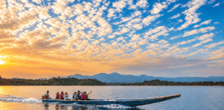 Personas realizan un paseo en lancha por un lago al atardecer, con montañas al fondo.