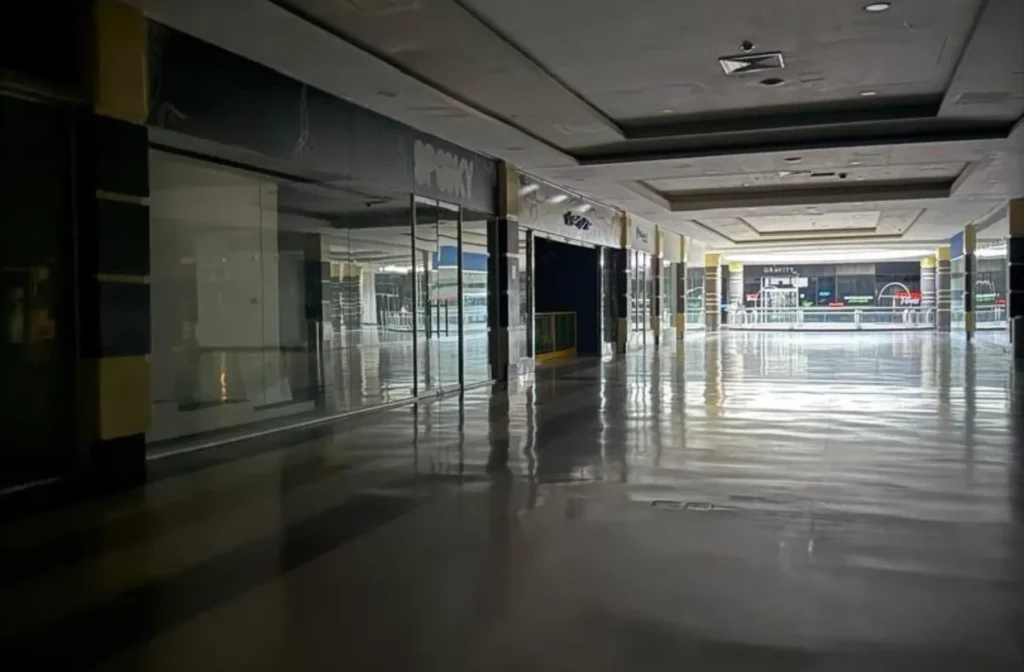Pasillos y locales de un centro comercial en penumbra durante una interrupción del servicio eléctrico.