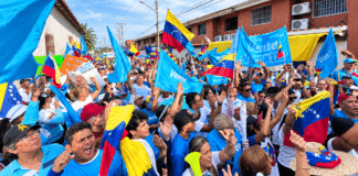 Banderas de Venezuela y estandartes azules de Vente Venezuela ondean durante una concentración política en el estado Portuguesa.