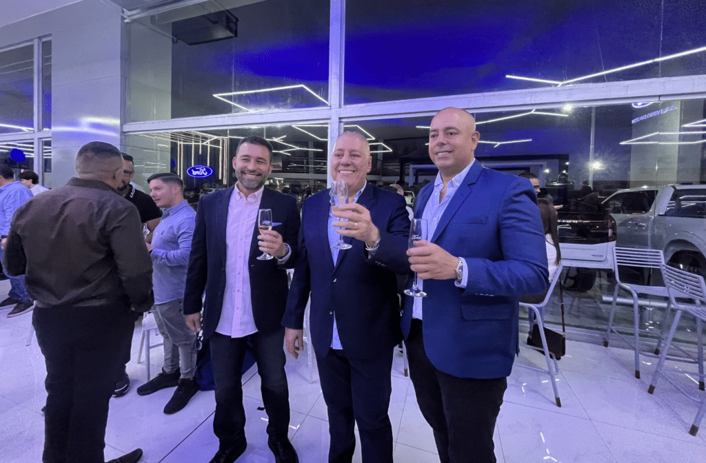 Tres ejecutivos brindan con copas durante la inauguración de Motores Oshima en Acarigua.