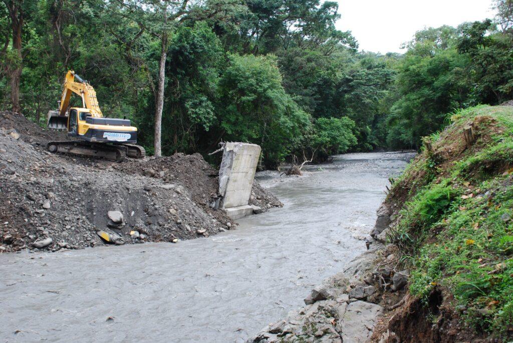 Estribo de concreto volcado en el cauce del río Ospino junto a maquinaria pesada que trabaja en la zona afectada.