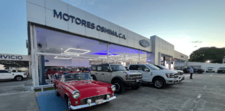 Fachada de Motores Oshima en Acarigua con un Ford Thunderbird clásico, una Bronco y una pickup F-150 en exhibición.
