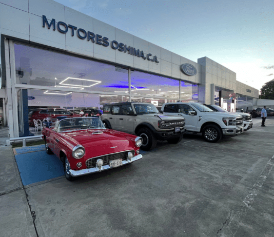 Fachada de Motores Oshima en Acarigua con un Ford Thunderbird clásico, una Bronco y una pickup F-150 en exhibición.