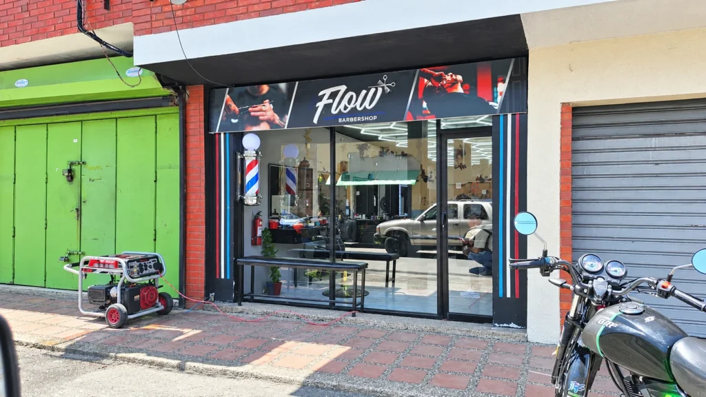 Generador eléctrico portátil instalado frente a la fachada del establecimiento Flow Barbershop.