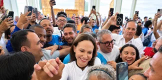 María Corina Machado saluda a una persona mientras avanza entre una multitud dentro de la iglesia de Santa Rosa, en Lara.
