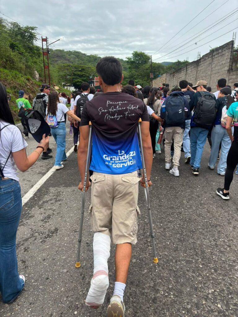 Joven peregrino con una pierna enyesada avanza con muletas durante la Marcha por la Fe y la Paz hacia Isnotú.