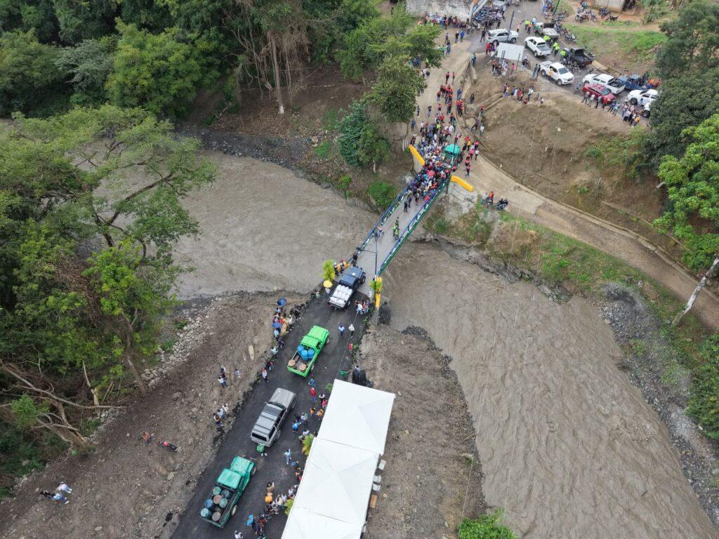 Vista aérea del puente sobre el río Ospino con vehículos y habitantes durante su inauguración.
